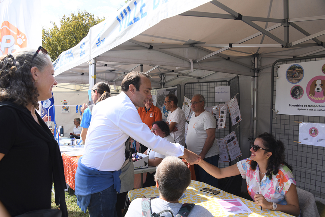 Pendant la Fête des animaux 2024, Jérémie Bréaud, le Maire, accompagné de Sandrien Berthet, Conseillère Municipale déléguée à la Vie Animale passent dan sles stands pour saluer les exposants, pendnat que des habitants visitent aussi les stands.