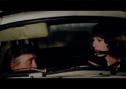 Dans une voiture, la nuit, un homme et une femme discutent en se regardant, l'air inquiet.