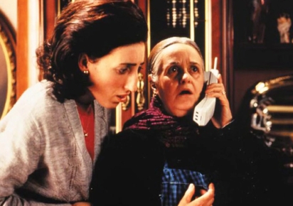 Photogramme issu du film La Fleur de mon secret. Deux femmes en plan moyen dont une plus agée est au téléphone et semble bouleversée. L'autre écoute à côté et semble bouleversée également.