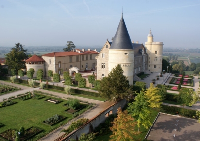 vue du chateau de Bouthéon, depuis le haut. Deux ailes de bâtiments face à face, encadrées chacunes par deux tours, dans un espace botanique.