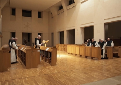 une dizaine de moines évoluent dans le choeur d'une chapelle moderne au sein de l'abbaye de Clairvaux.